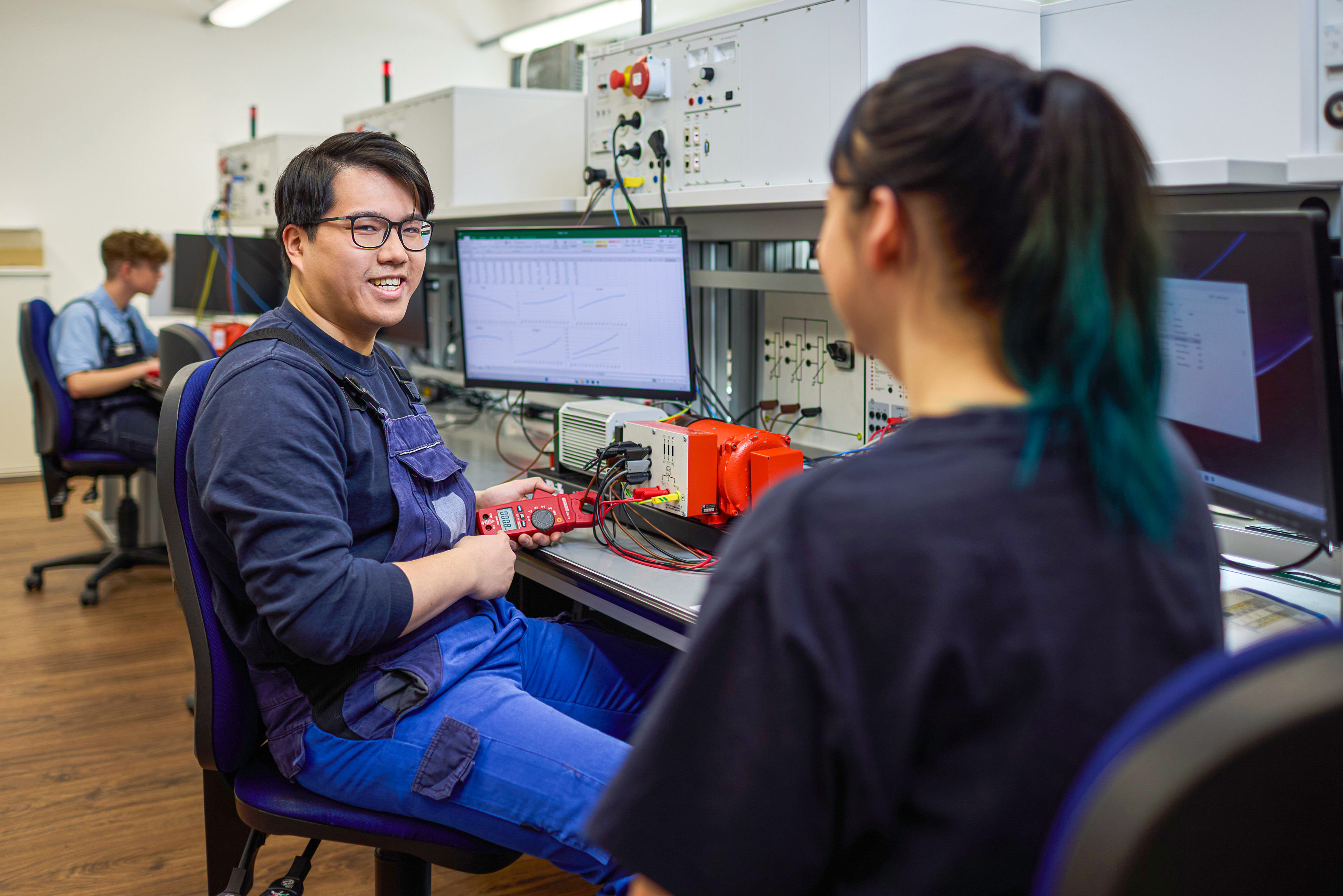Auszubildender am Arbeitsplatz mit einem Messgerät in der Hand