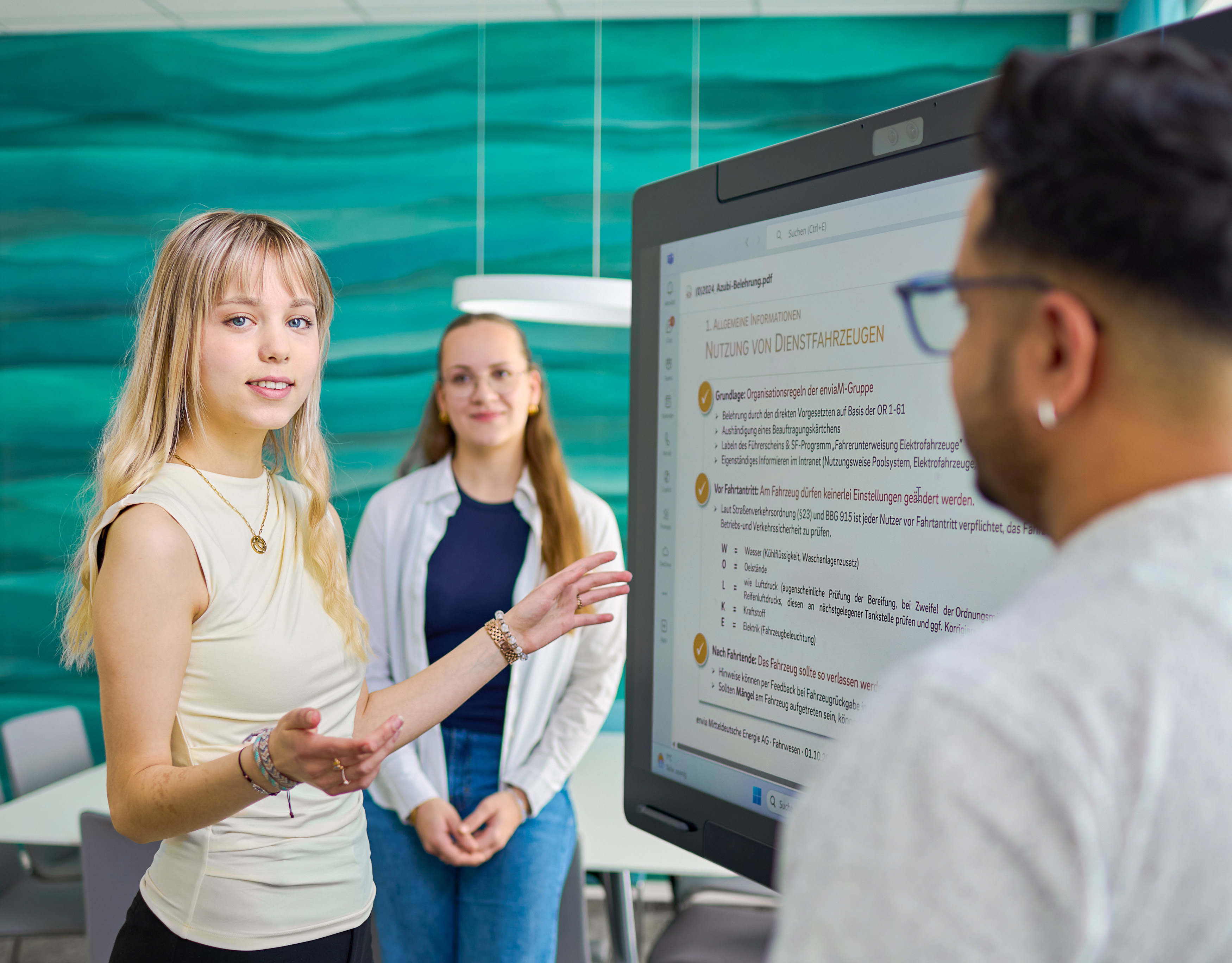 junge Frau erklärt etwas vor einem Bildschirm