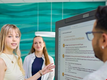 Frau vor Bildschirm junge Frau erklärt etwas vor einem Bildschirm