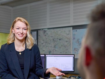 junge-frau-sitzt-auf-tisch junge Frau sitzt auf der Tischkante und erklärt einem Mann etwas