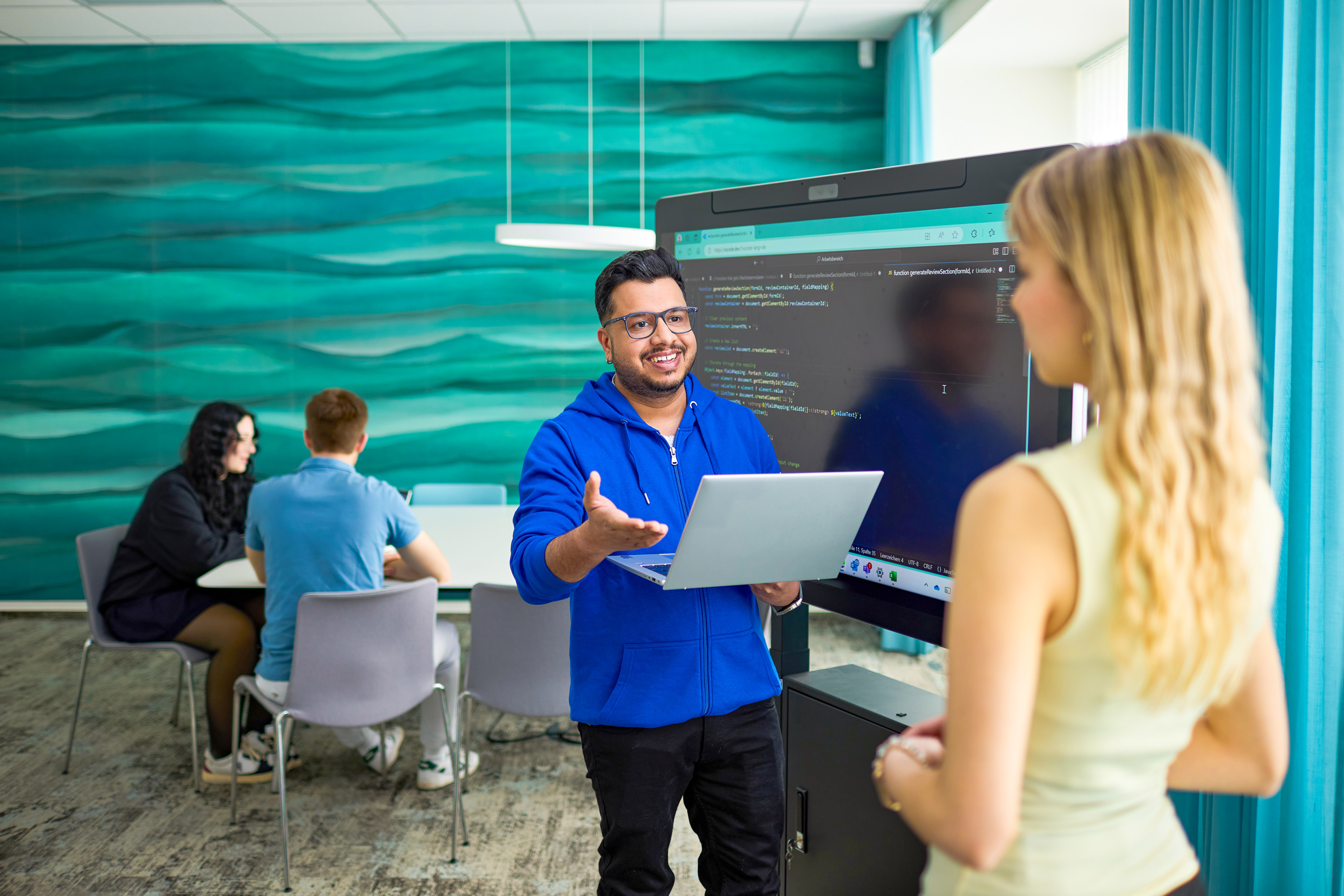 Mann mit Laptop und blonde Frau reden miteinander