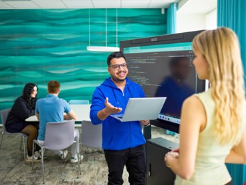 Mann mit Laptop Mann mit Laptop und blonde Frau reden miteinander